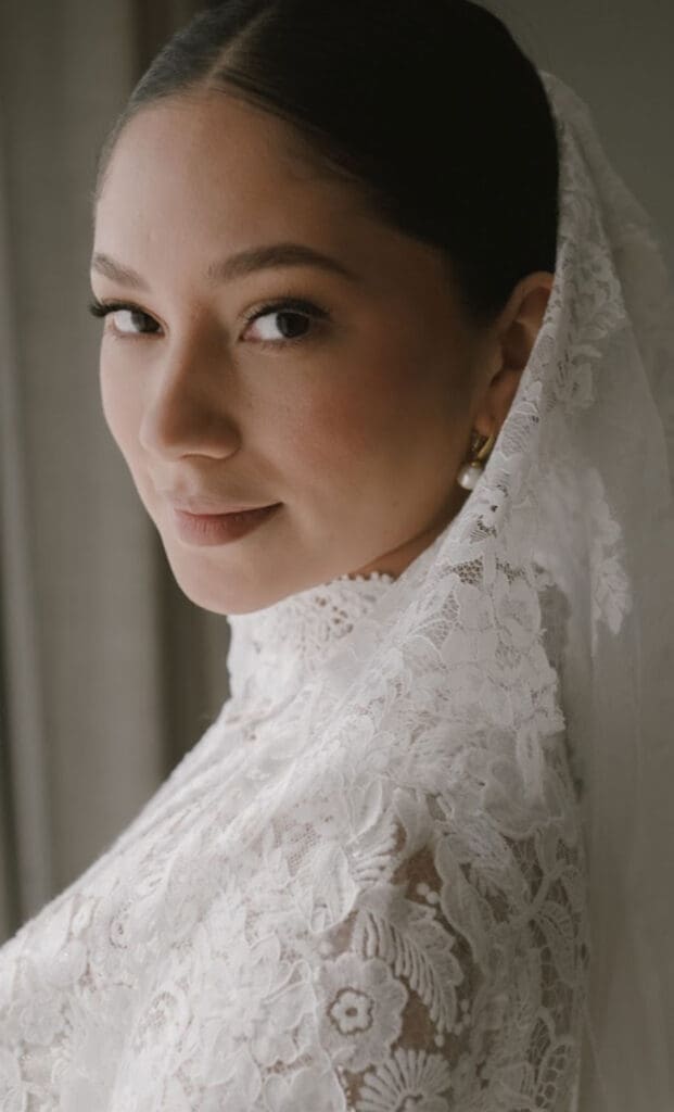 A bride in a lace high-neck wedding dress with a vintage-inspired veil
