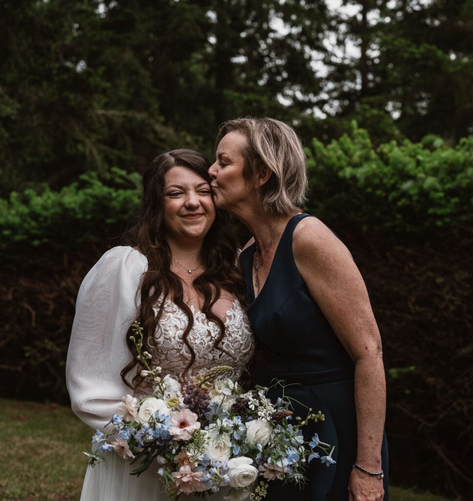 Mother kissing bride on cheek