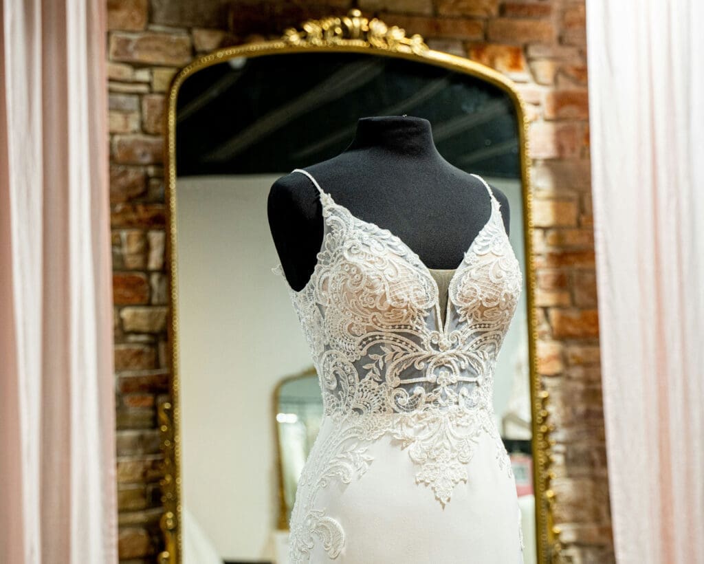 Lace wedding dress displayed on mannequin in fitting room